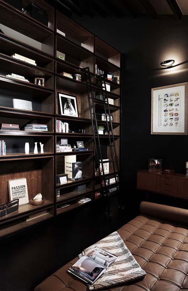 This dark library with black accents and buttery tan leather is a dream reading room.