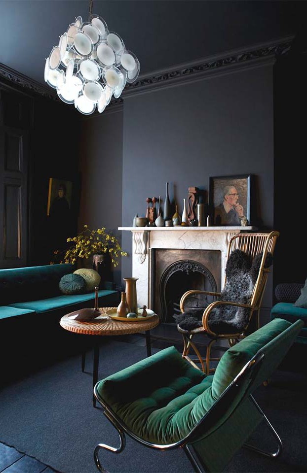 The teal and green furniture really pops against the dark walls.